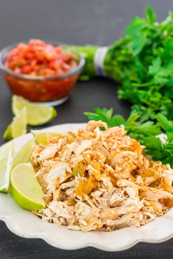 a plate of crockpot mexican chicken garnished with lime wedges