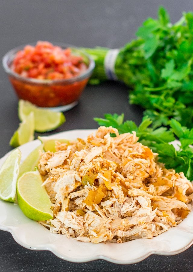 a plate of crockpot mexican chicken garnished with lime wedges
