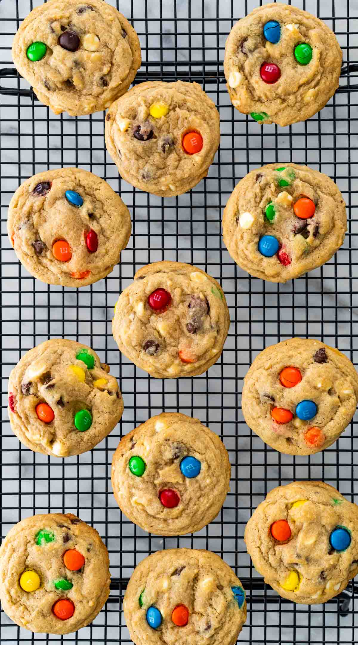 overhead shot of m&m cookies cooling on black cooling rack.