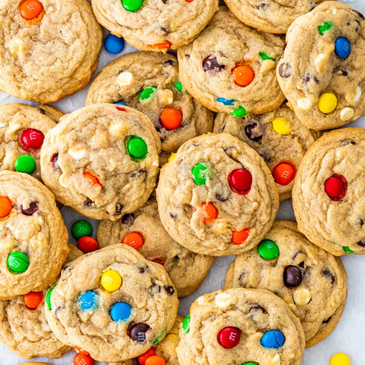 overhead shot of m&m cookies piled together on parchment paper.