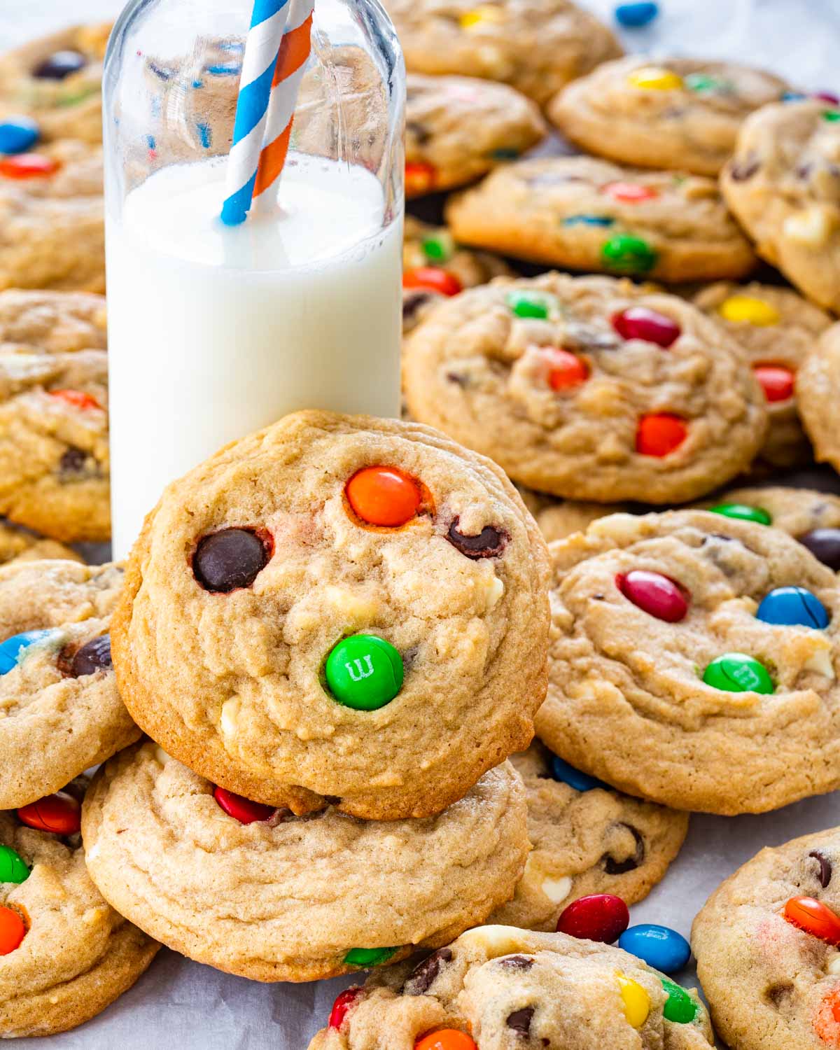 a pile of m&m cookies and a bottle of milk.