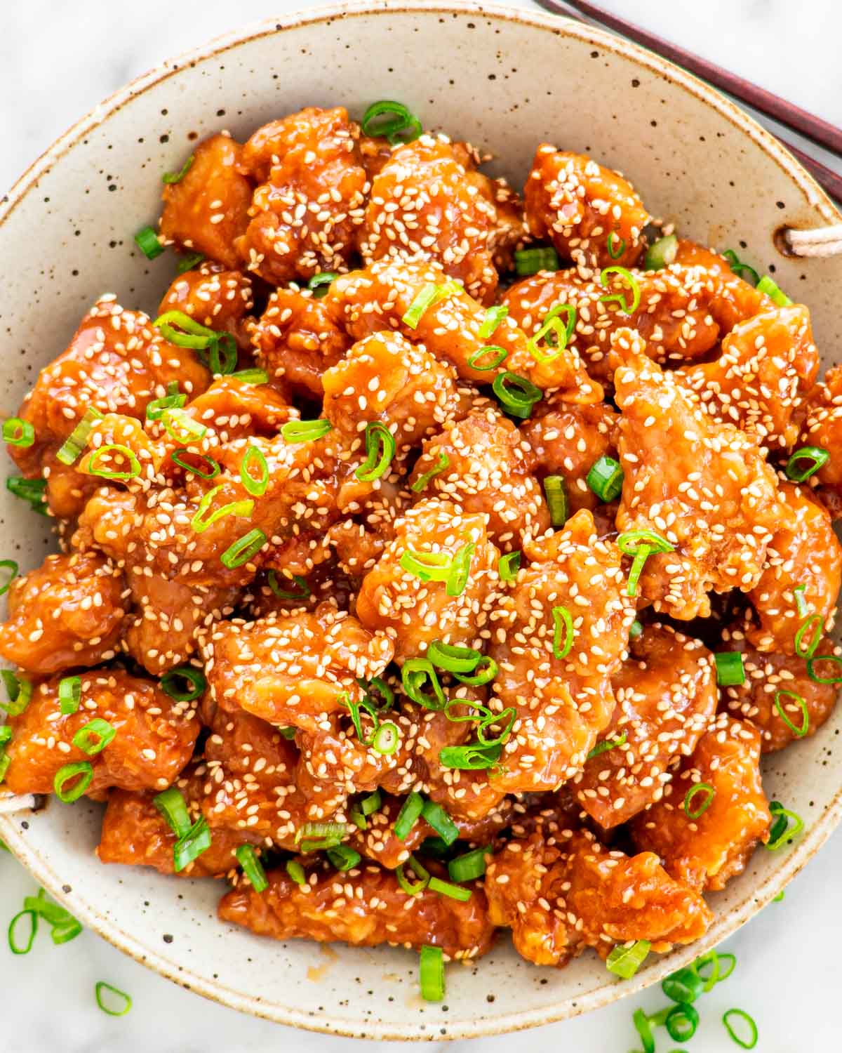sesame chicken garnished with green onions in a fancy bowl