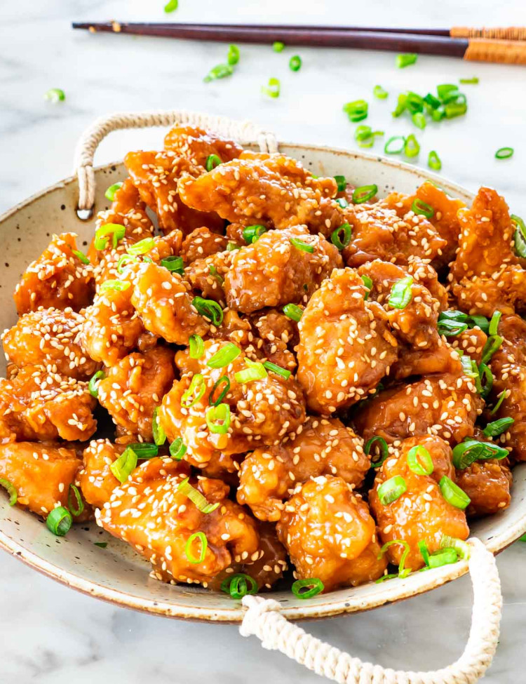 sesame chicken garnished with green onions in a fancy bowl