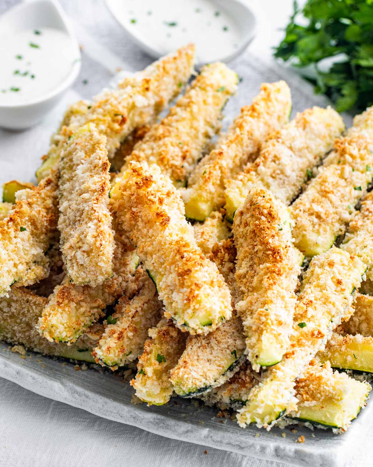 baked zucchini sticks stacked on a serving platter.