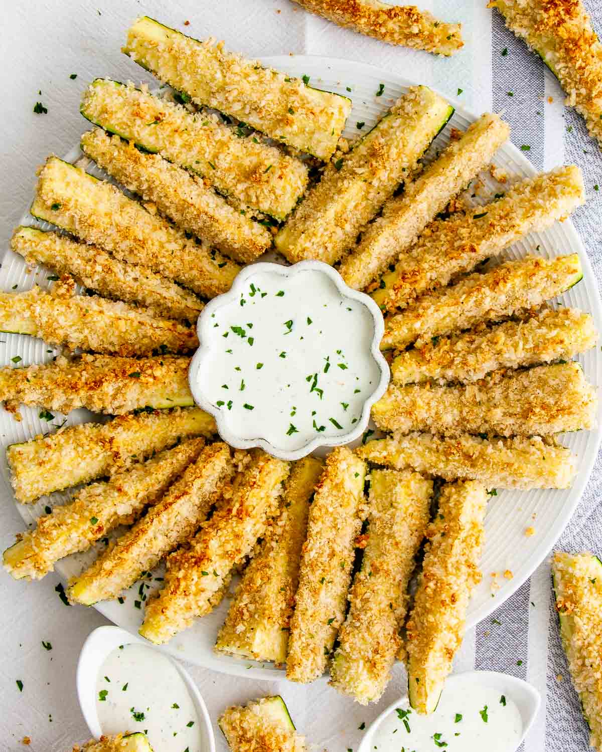 baked parmesan zucchini sticks on a serving platter with a bowl of ranch dressing.