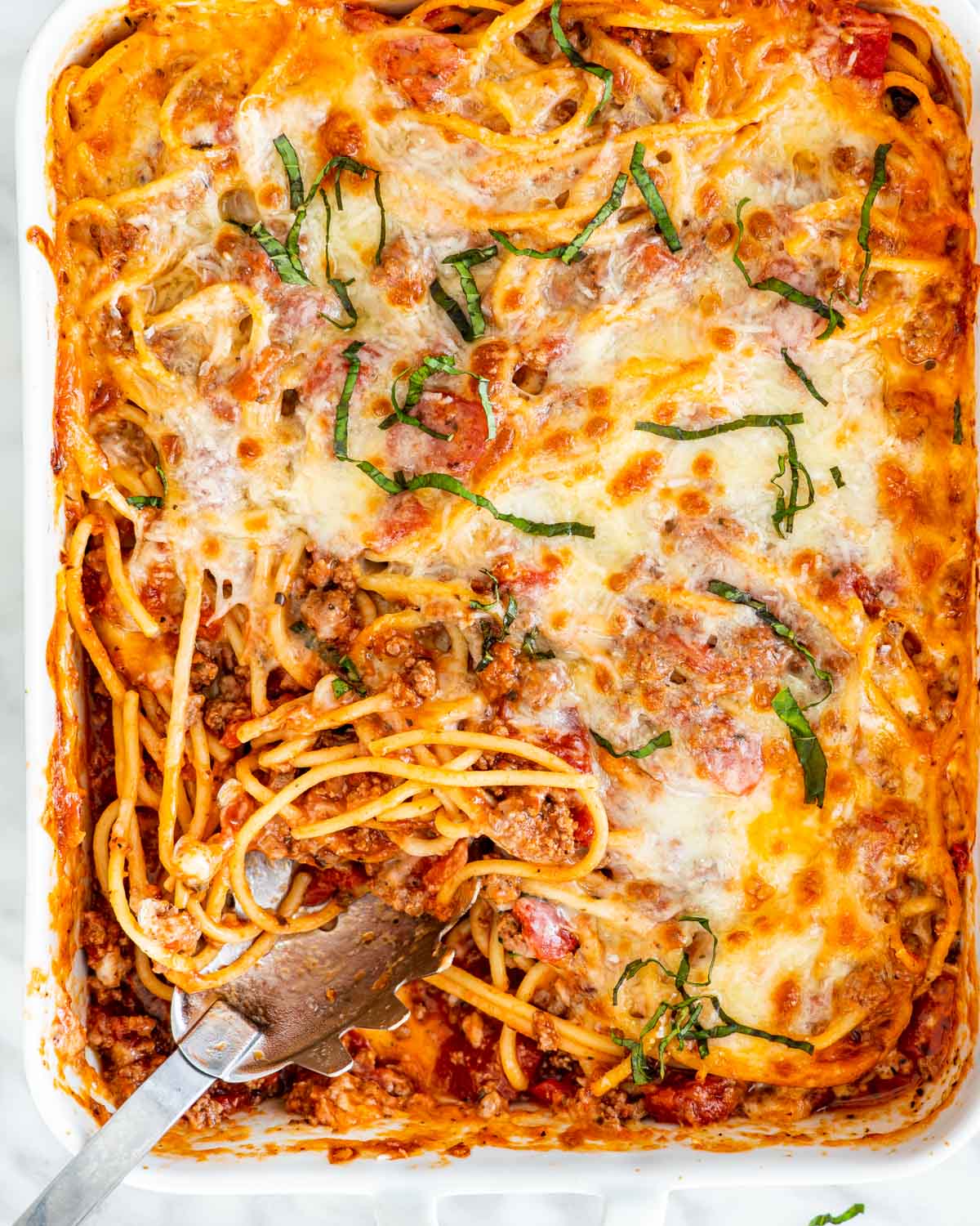 overhead shot of baked spaghetti casserole in a dish with a spoon in it
