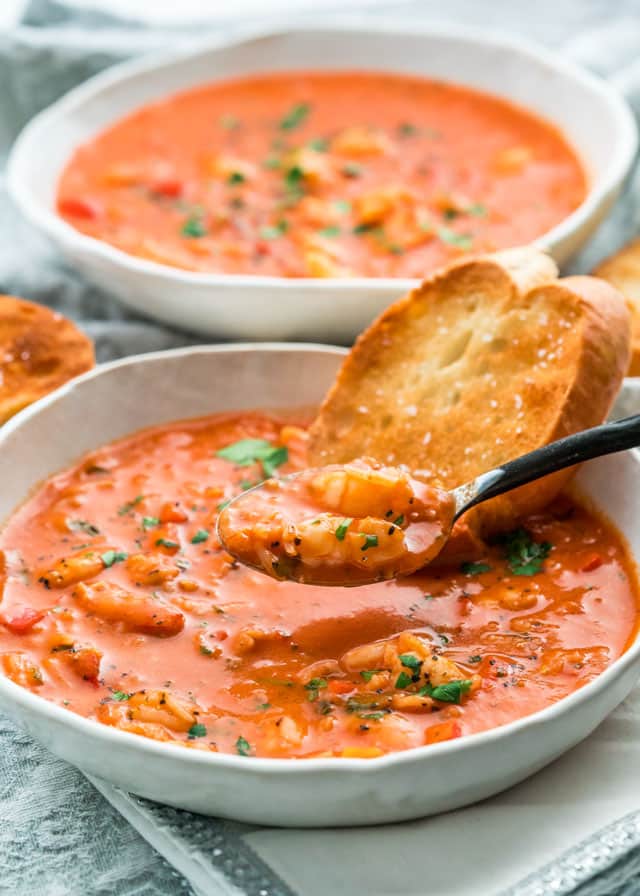 two bowls of Brazilian Shrimp Soup in white plates and a slice of toasted crusty bread