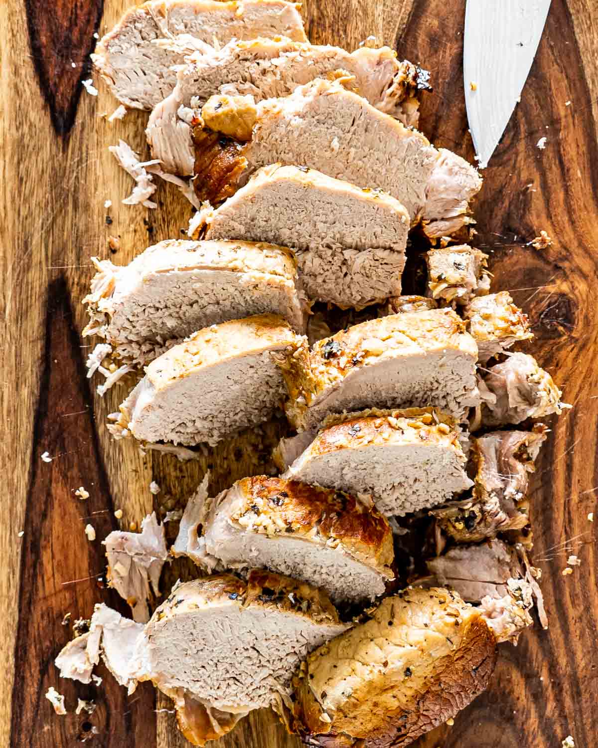 pork loin roast that was made in a crockpot sliced on a cutting board.