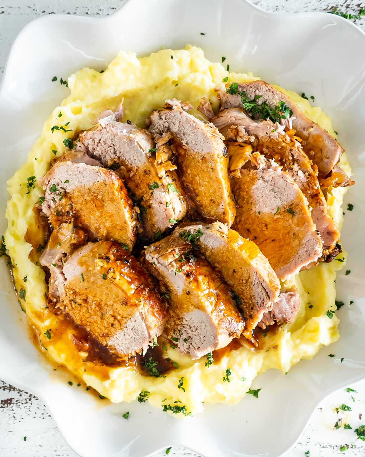sliced pork loin roast on a bed of mashed potatoes.