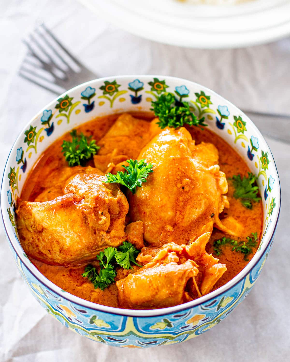 Crockpot Thai Chicken in a big blue and white bowl garnished with parsley