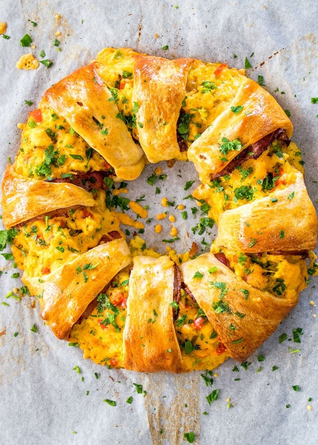Crescent Bacon Breakfast Ring garnished with parsley on parchment paper
