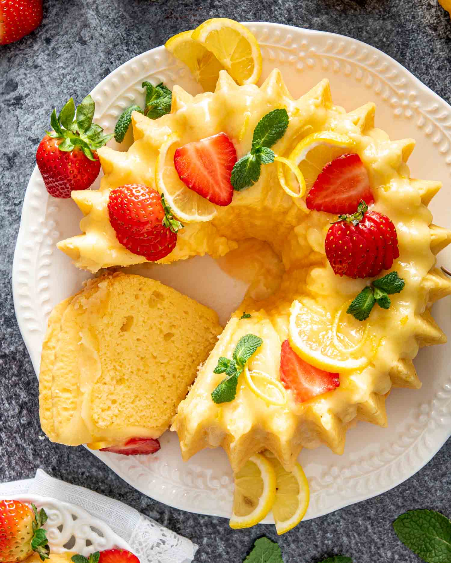 a lemon chiffon cake on a platter garnished with lemon slices and strawberries.