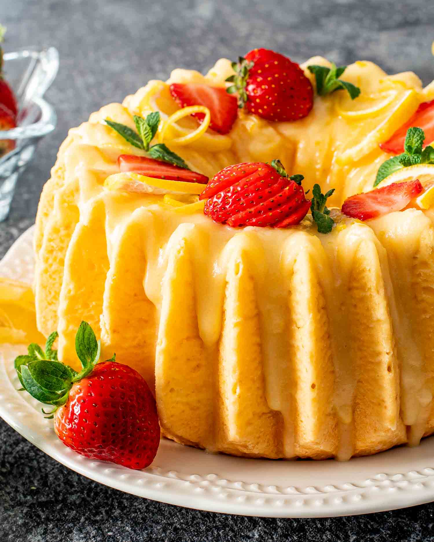 a lemon chiffon cake on a platter garnished with lemon slices and strawberries.