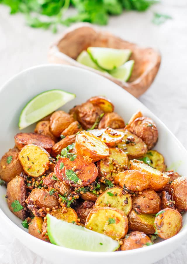 A bowl of Roasted Potatoes with East Indian Spices garnished with lime wedges