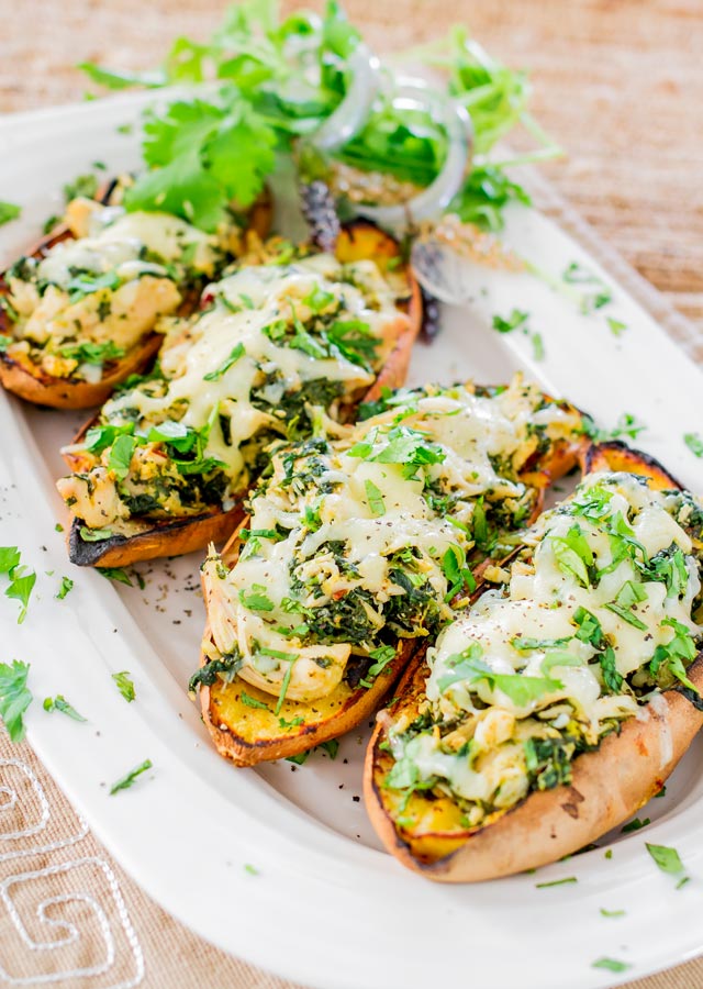  4 chipotle chicken stuffed sweet potato skins on a platter garnished with cilantro