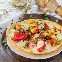 a grilled peach and prosciutto flatbread drizzled with balsamic on a plate
