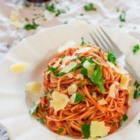 a bowl of spaghettini with blush sauce topped with fresh parmesan cheese