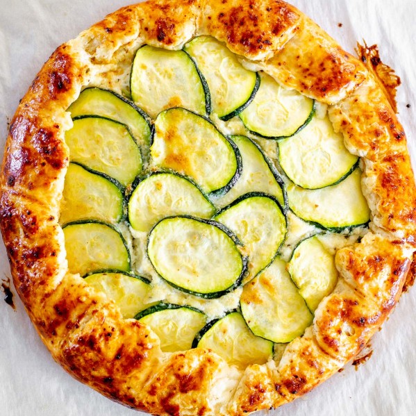 overhead shot of a zucchini ricotta galette fresh out of the oven on a baking sheet lined with parchment paper