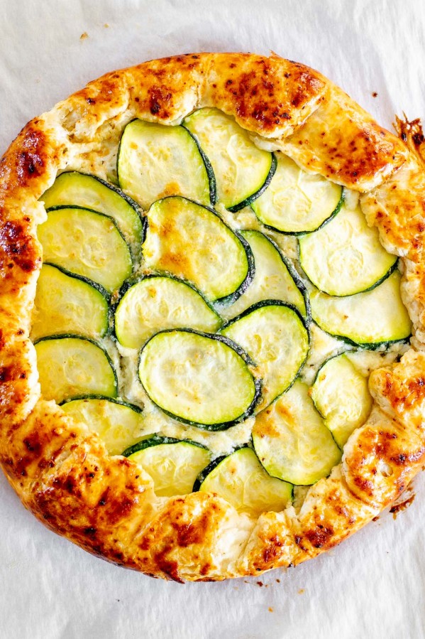 overhead shot of a zucchini ricotta galette fresh out of the oven on a baking sheet lined with parchment paper