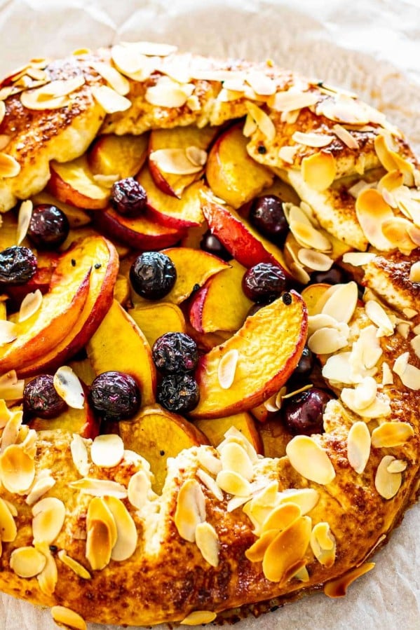 sideview shot of a beautiful peach galette fresh out of the oven with toasted almonds