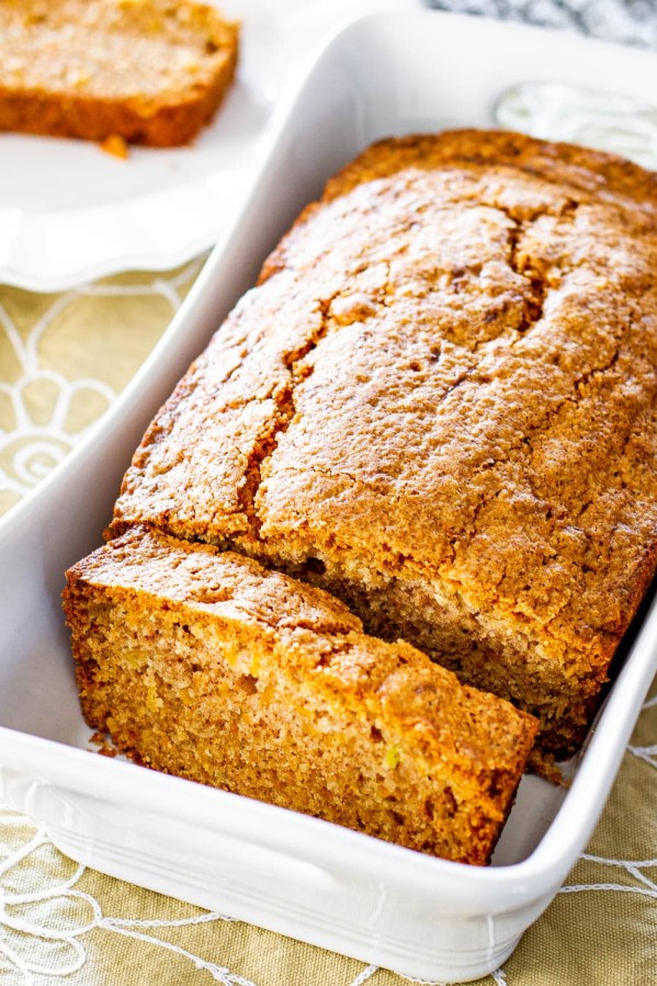 a cantaloupe tea loaf in a white loaf pan with a slice cut out