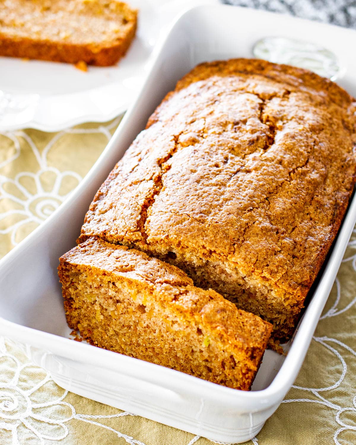 a cantaloupe tea loaf in a white loaf pan with a slice cut out