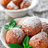 a bowl full of banana fritters dusted in powdered sugar