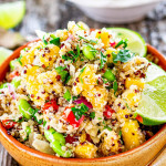 a bowl filled with a delicious quinoa salad loaded with fresh ingredients and garnished with parsley and lemon wedges