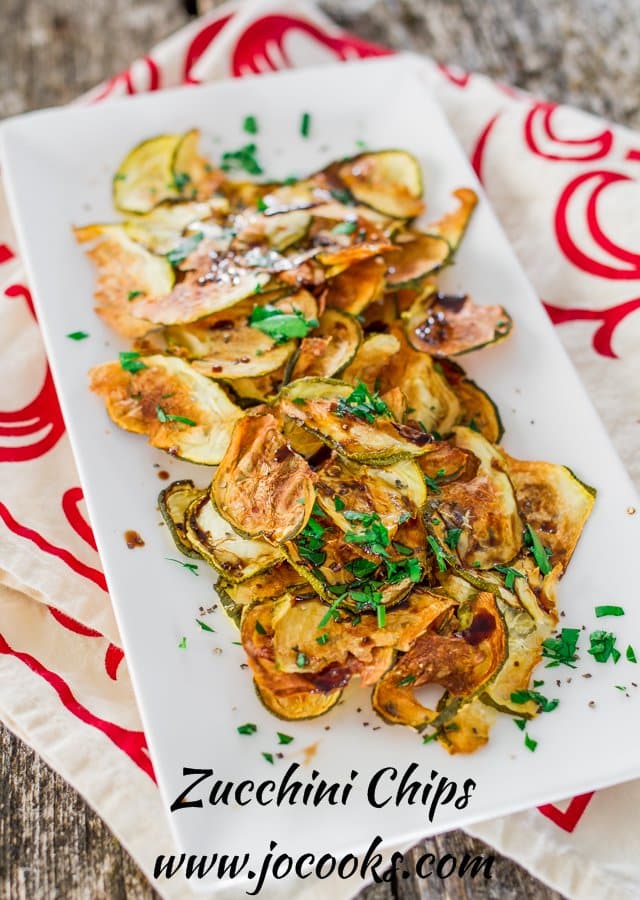 Baked Zucchini Chips on a white plate garnished with parsley