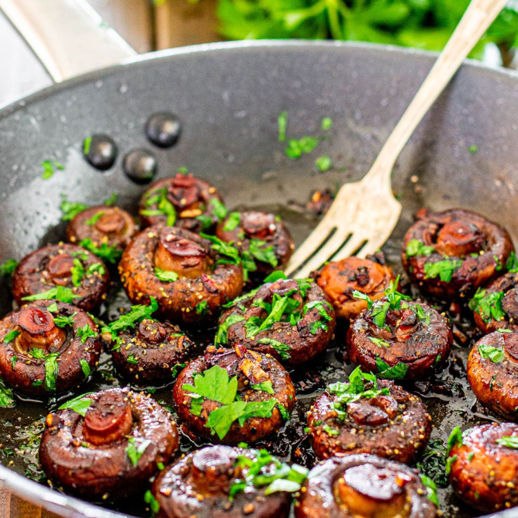 a skillet full of red wine garlic mushrooms with a fork resting in it