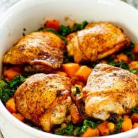 Close up shot of chicken thighs with sweet potato and kale bake