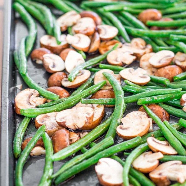 green beans and mushrooms on a baking sheet ready to be roasted on a