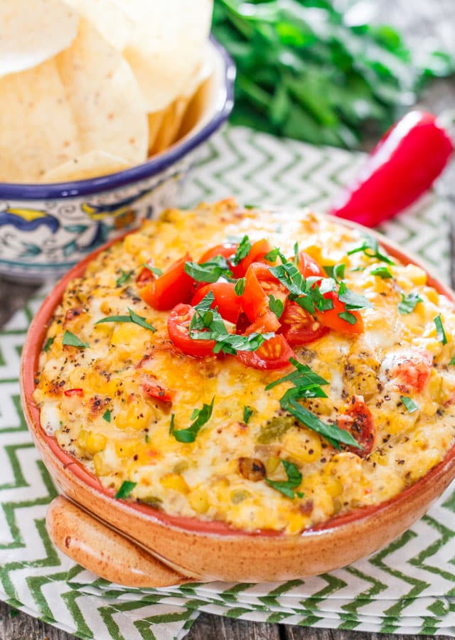 Spicy Cheesy Corn and Tomato Dip  in a bowl topped with tomatoes
