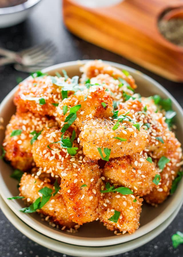Baked Honey Garlic Chicken in a bowl garnished with parsley and sesame seeds