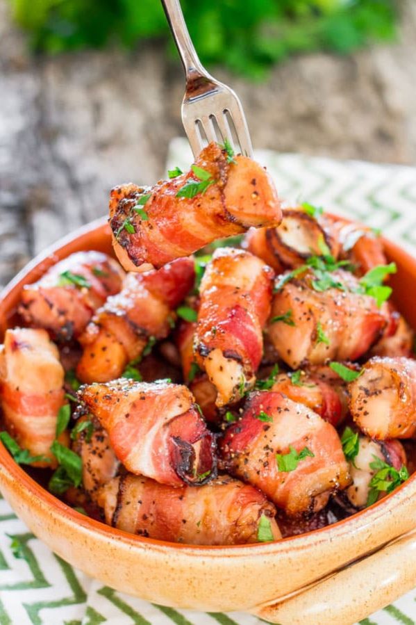 a bowl of sweet chicken bacon bites with a fork stuck in one