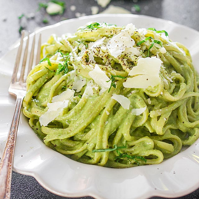 a plate of avocado and spinach pasta with grated parmesan cheese