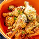 baked garlic and ginger chicken drumsticks in an orange bowl.