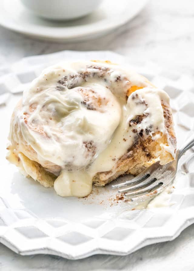Cinnabons Cinnamon Roll on a white plate with a fork 