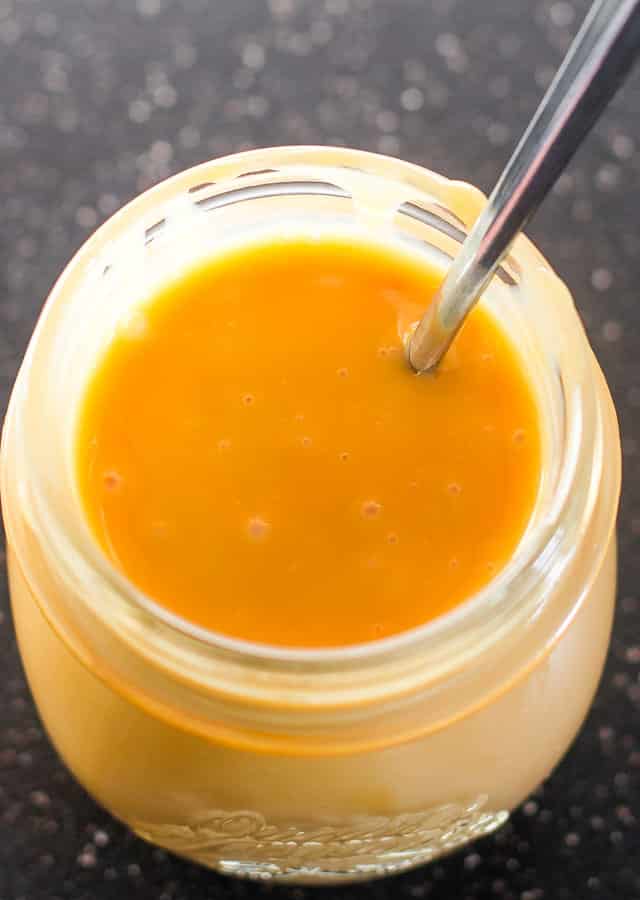 Top shot of 1 Ingredient Caramel Sauce in a jar with a spoon in it 