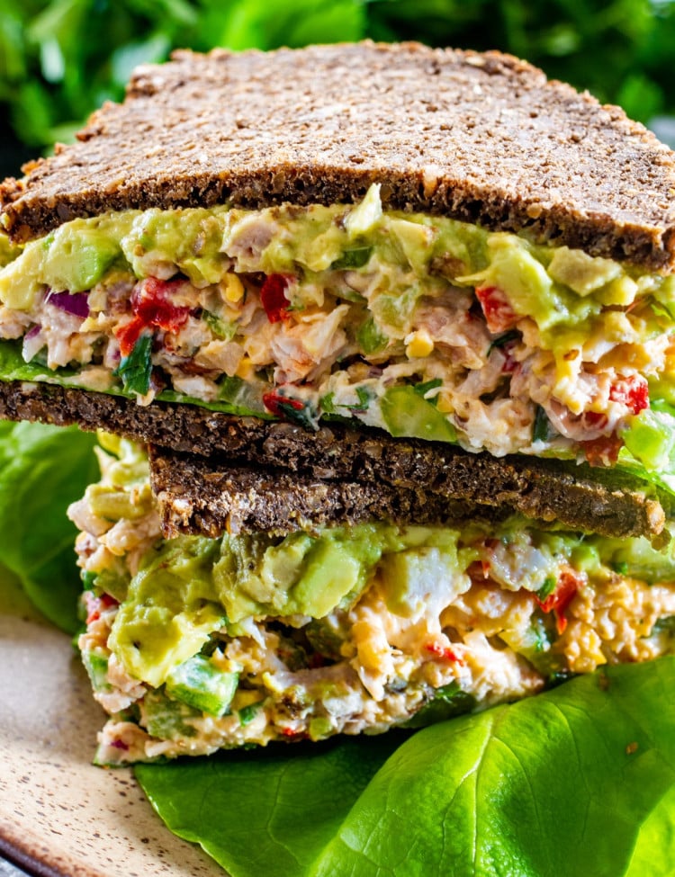 an avocado chicken salad sandwich cut in half and stacked, with the centers exposed