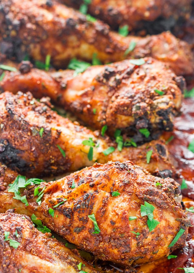 garlic and paprika chicken legs in a baking dish garnished with parsley