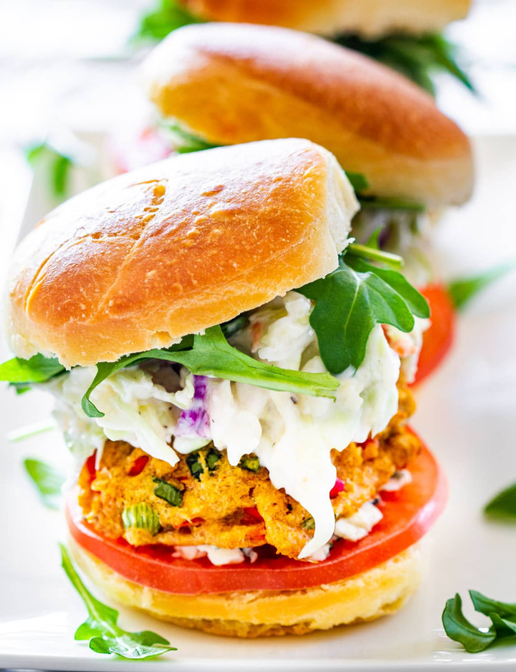 3 crab cake sliders on a white plate garnished with baby arugula