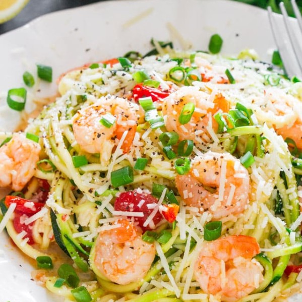 a plate full of shrimp scampi zoodles garnished with green onions