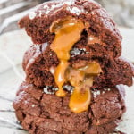 the inside of a split cookie is dripping down a stack of salted rolo and nutella double chocolate cookies.