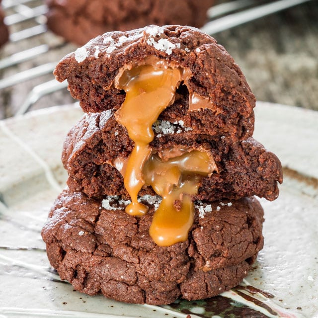 Salted Rolo and Nutella Stuffed Double Chocolate Cookies stacked on top of each other, two with melted caramel center exposed