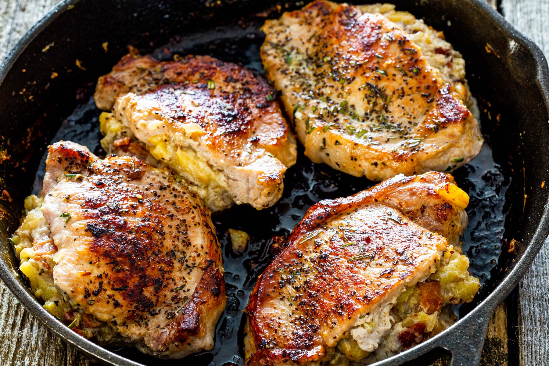 4 stuffed pork chops with apple, bacon and blue cheese in a black skillet