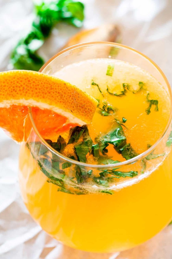 a grapefruit mimosa in a glass garnished with red grapefruit and basil