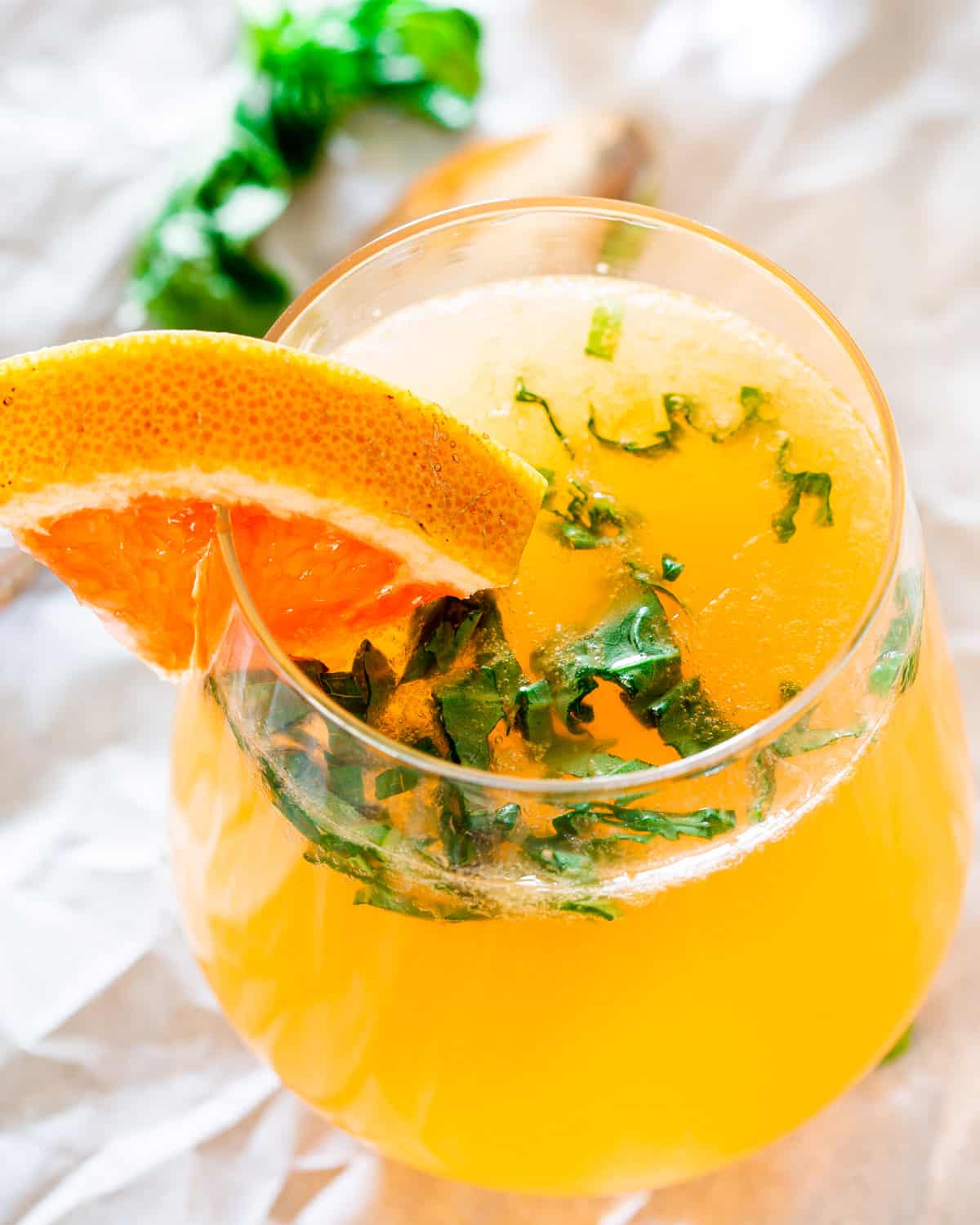 a grapefruit mimosa in a glass garnished with red grapefruit and basil