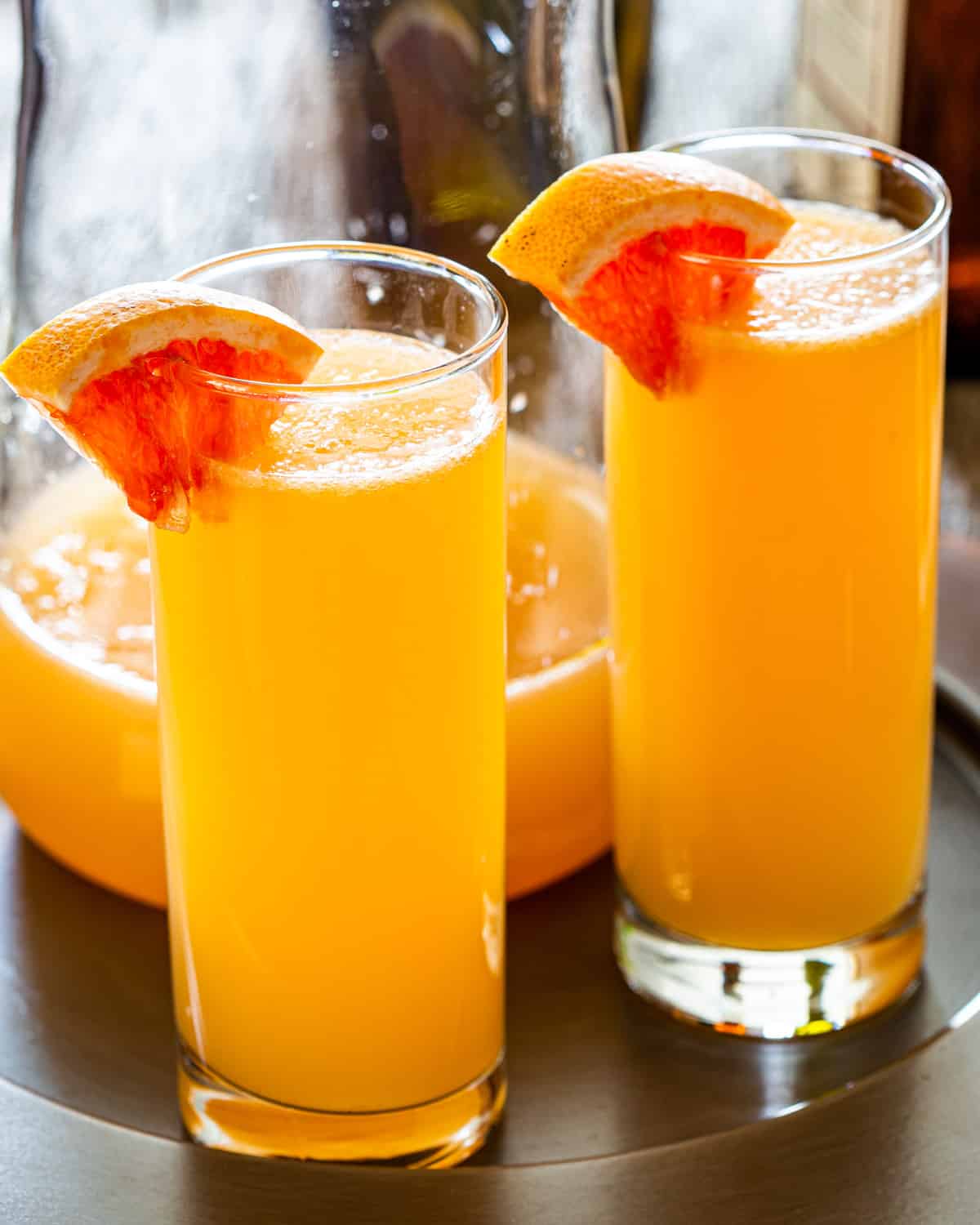 two glasses filled with grapefruit mimosas and garnished with red grapefruit slice