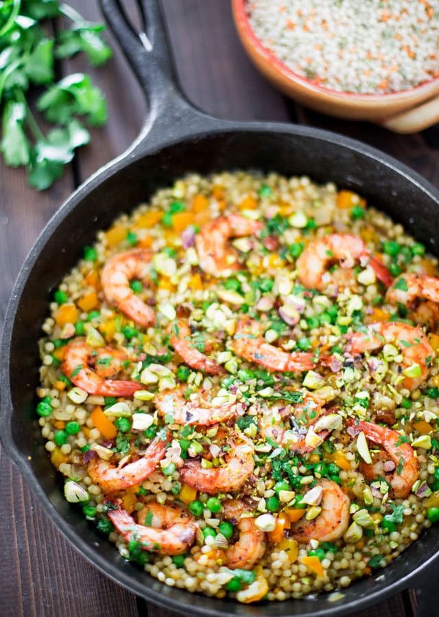 One Pot Couscous with Shrimp and Peas in a skillet topped with parsley